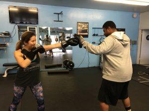 A woman practicing boxing with a coach