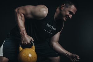 A man lifting a yellow kettlebell with one hand