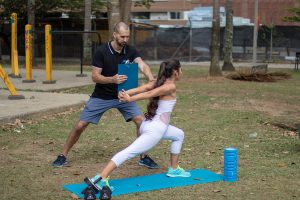 A training coach assisting a lady on her workout