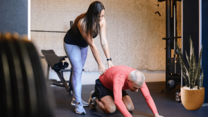 A lady trainer assisting an old man in his workout