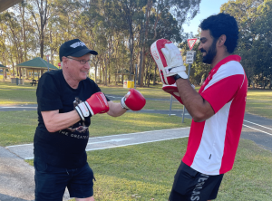 An old man wearing gloves and train with a personal trainer